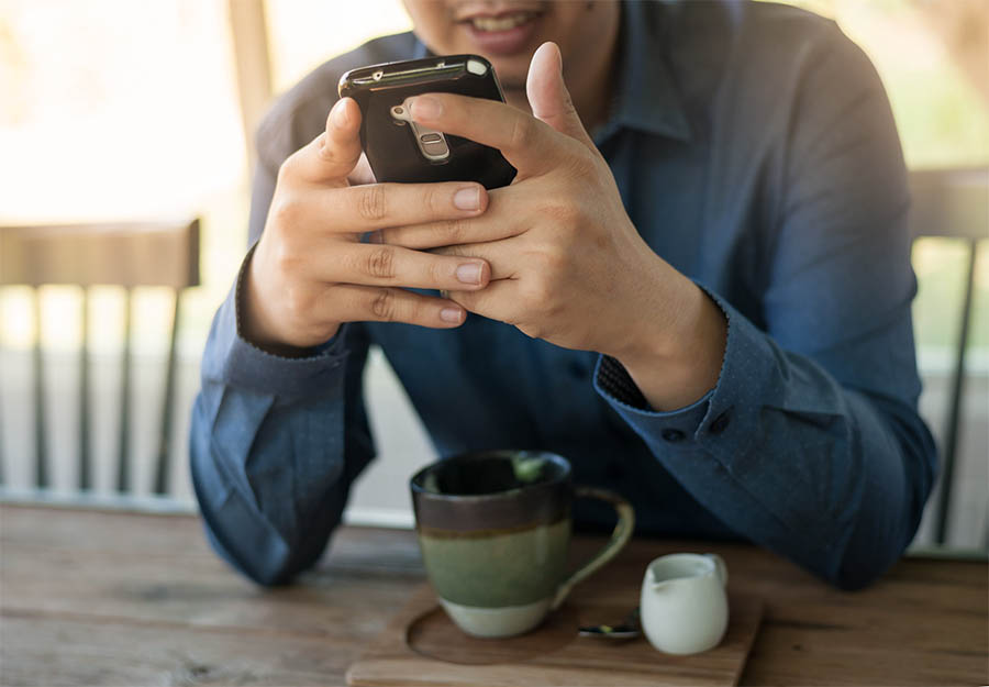 Een man zit aan zijn bureau en kijkt naar zijn telefoon